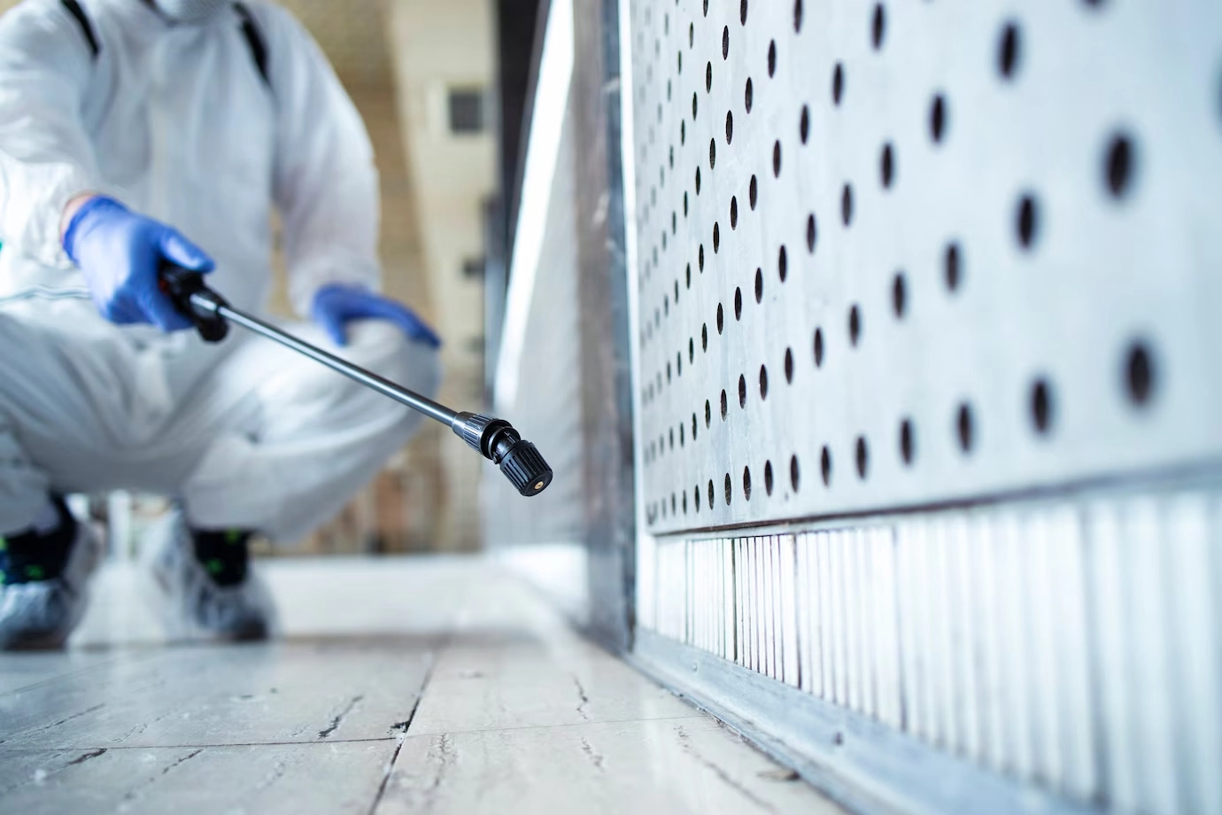 Unrecognizable person in white chemical protection suit doing disinfection